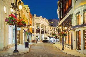 Photo of Rodeo Drive with illuminated stores in Beverly Hills, Los Angeles, California, USA at twilight blue hour.